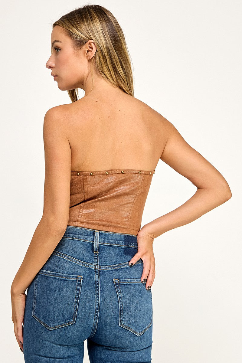Woman wearing a black strapless top and blue jeans on a white background