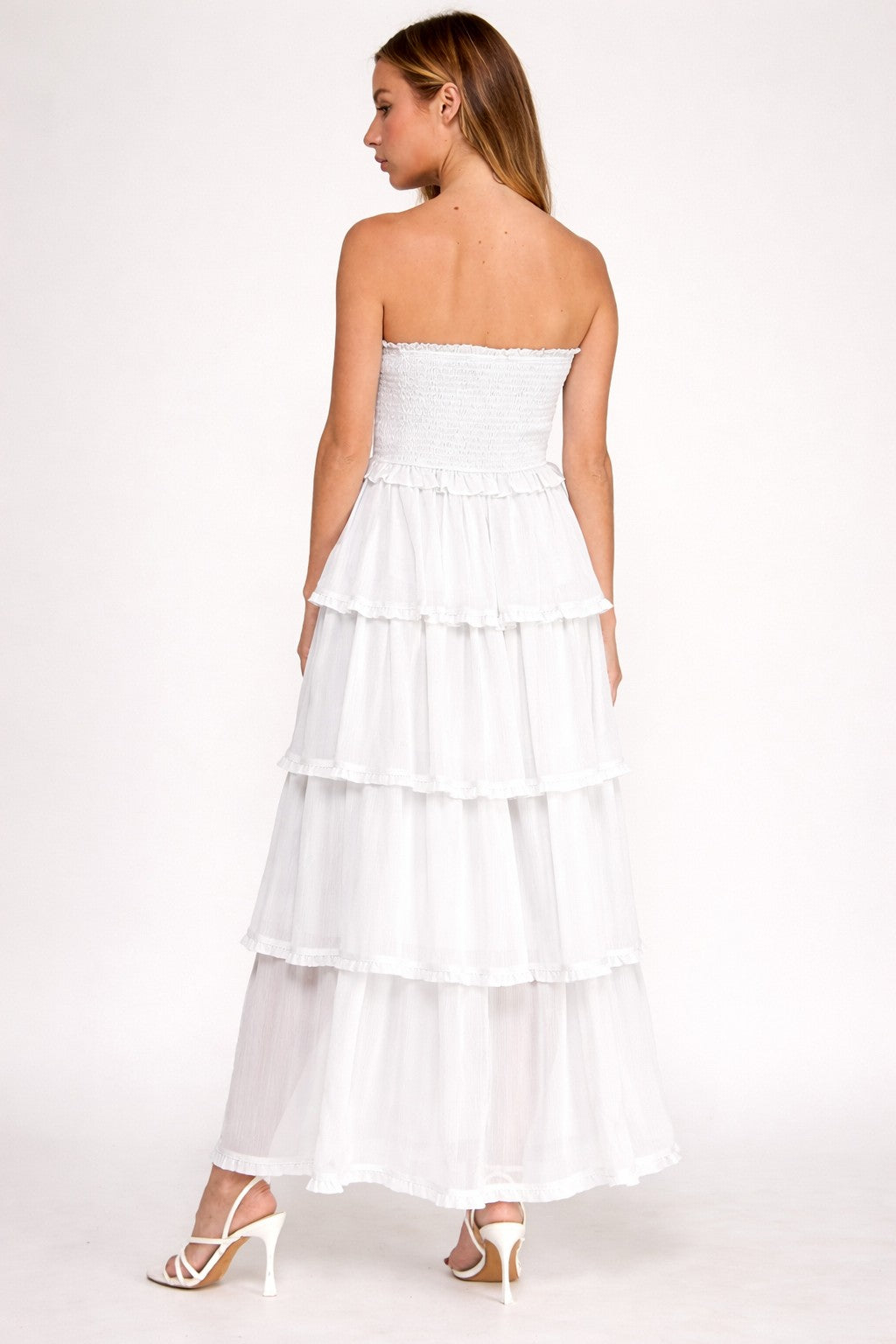 Woman wearing a white strapless dress with layered skirt on a white background