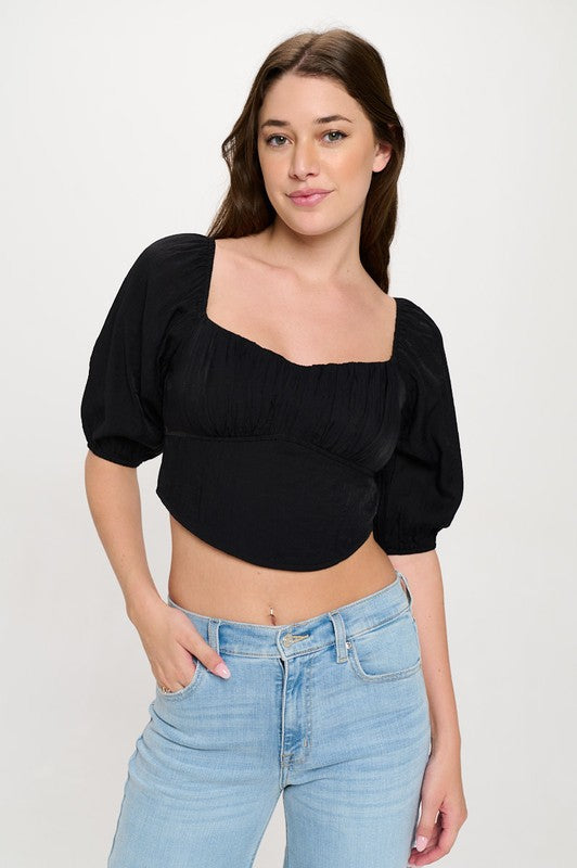 Woman wearing a off-shoulder top with white pants on a light gray background