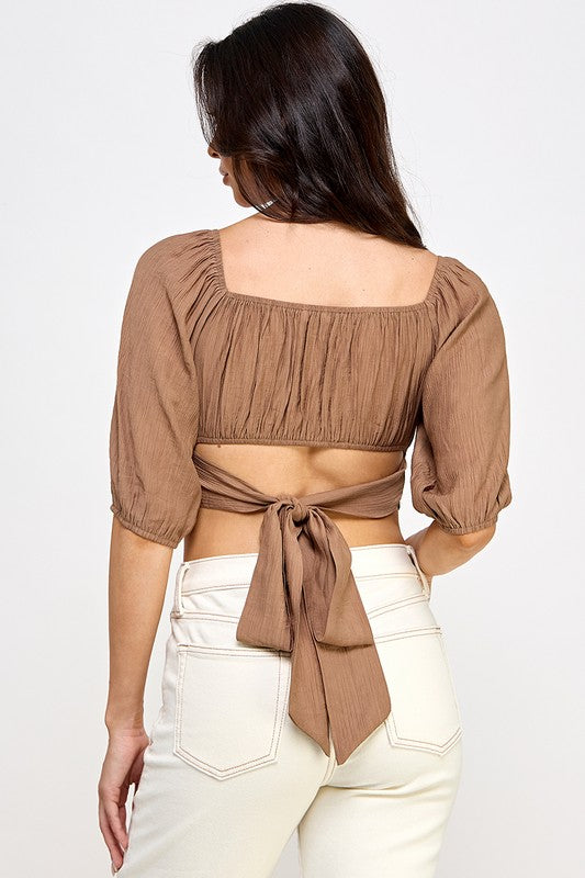 Woman wearing a off-shoulder top with white pants on a light gray background