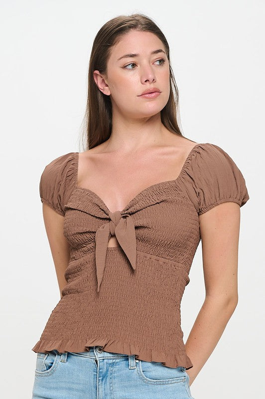 Woman wearing a top with a bow detail on a white background