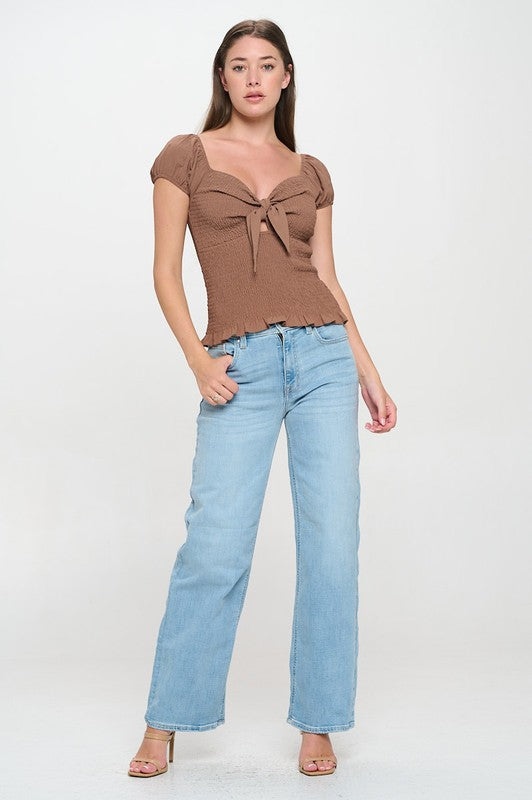 Woman wearing a top with a bow detail on a white background