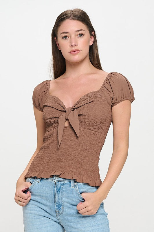 Woman wearing a top with a bow detail on a white background