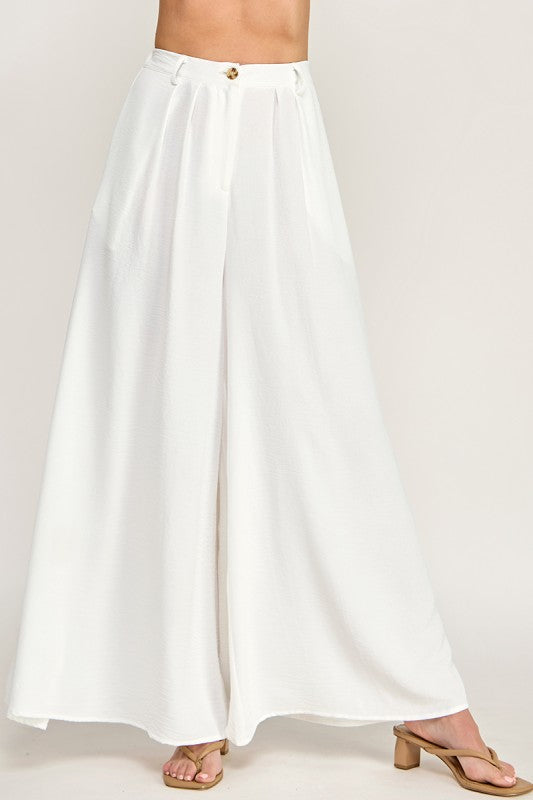 Woman wearing a beige top and white pants on a white background