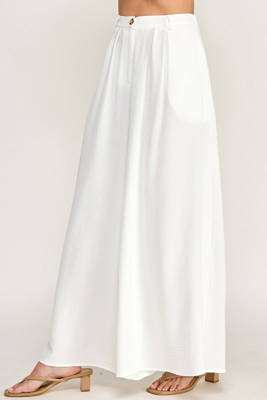 Woman wearing a beige top and white pants on a white background