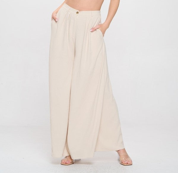 Woman wearing a beige top and white pants on a white background
