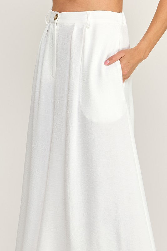 Woman wearing a beige top and white pants on a white background