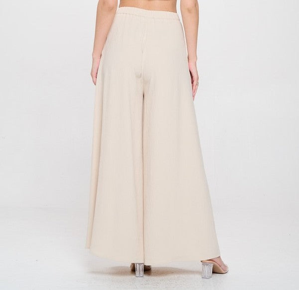 Woman wearing a beige top and white pants on a white background