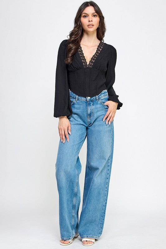 Woman wearing a blouse with long sleeves and white pants on a plain background