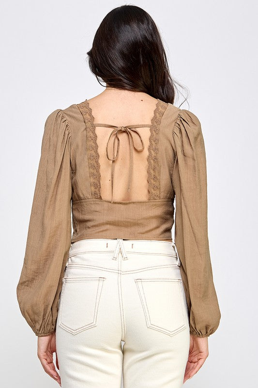 Woman wearing a blouse with long sleeves and white pants on a plain background
