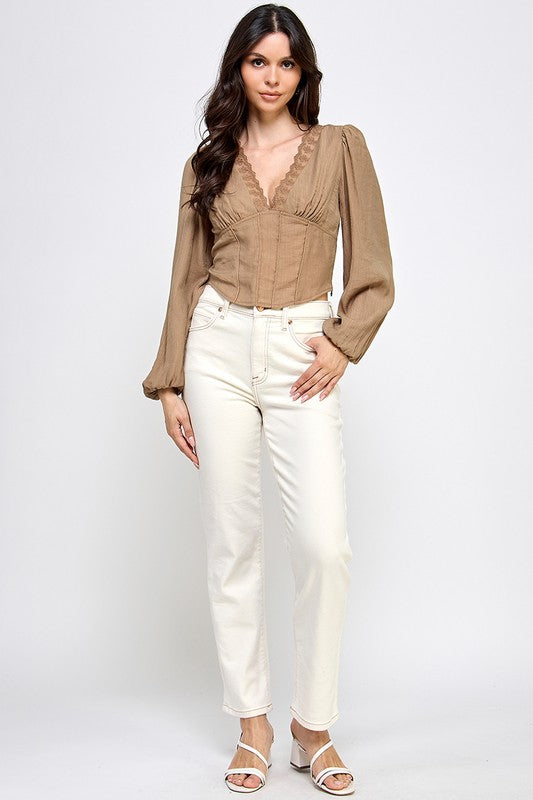 Woman wearing a blouse with long sleeves and white pants on a plain background