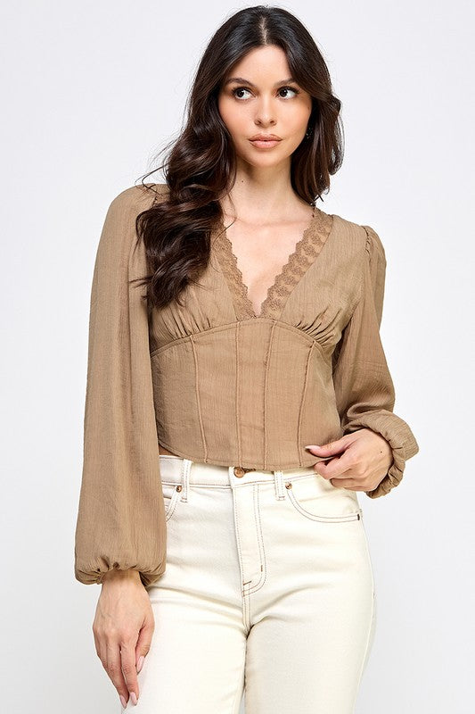 Woman wearing a blouse with long sleeves and white pants on a plain background