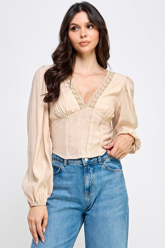 Woman wearing a blouse with long sleeves and white pants on a plain background
