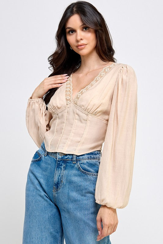 Woman wearing a blouse with long sleeves and white pants on a plain background