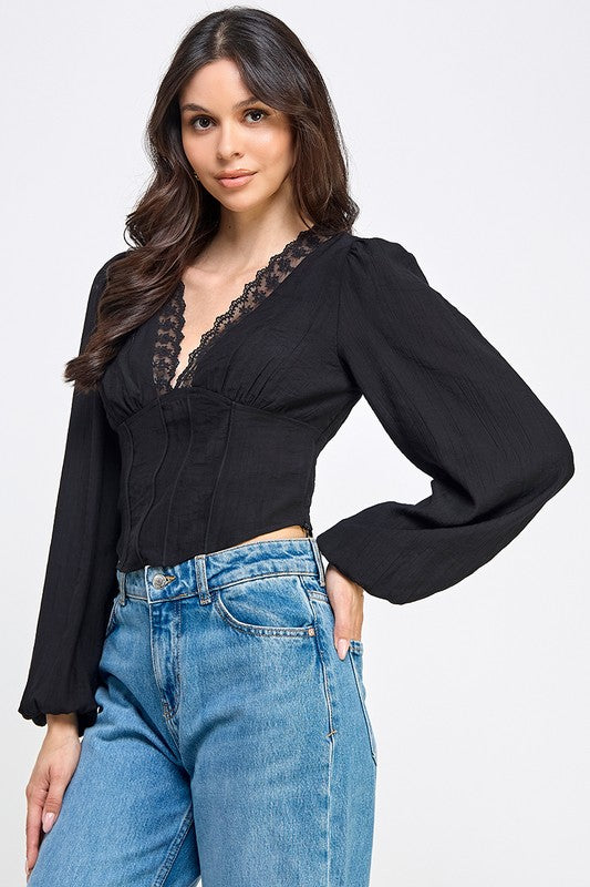 Woman wearing a blouse with long sleeves and white pants on a plain background