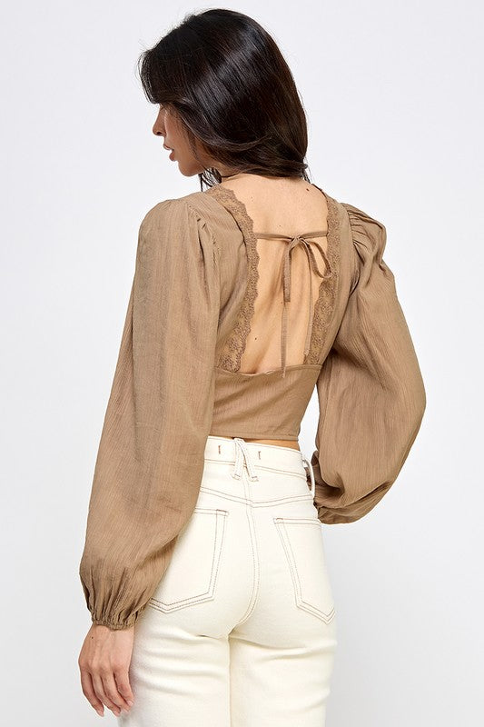 Woman wearing a blouse with long sleeves and white pants on a plain background