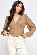Woman wearing a blouse with long sleeves and white pants on a plain background