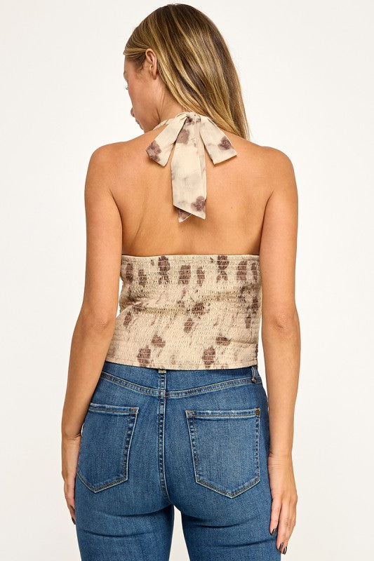 Woman wearing a floral halter top and blue jeans on a white background