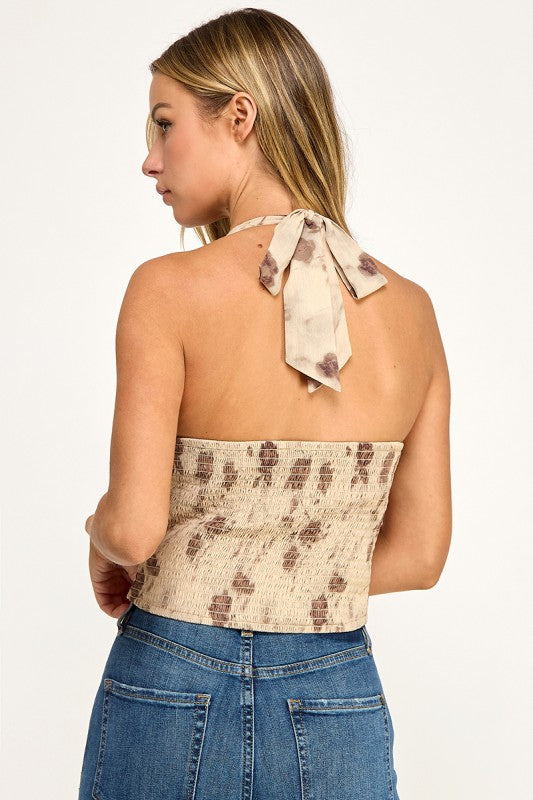 Woman wearing a floral halter top and blue jeans on a white background