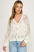 A woman wearing the SW5690 V-neckline, button-front long sleeves open-knit cardigan in cream with light blue jeans stands against a plain white background—an ideal transitional fashion look.