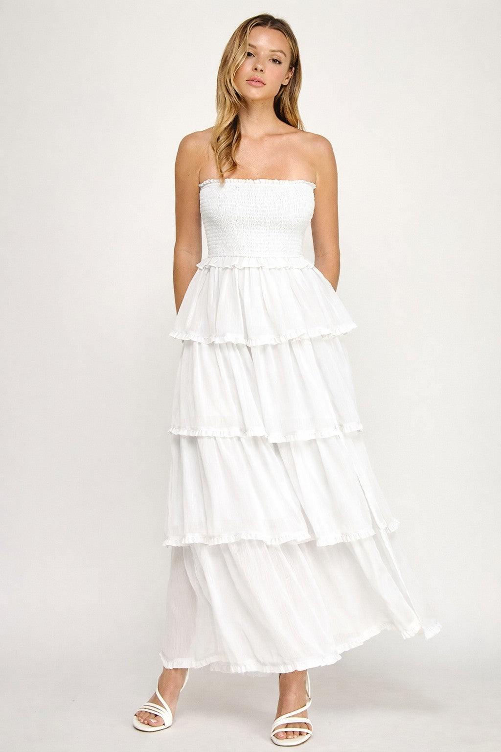 Woman wearing a white strapless dress with layered skirt on a white background
